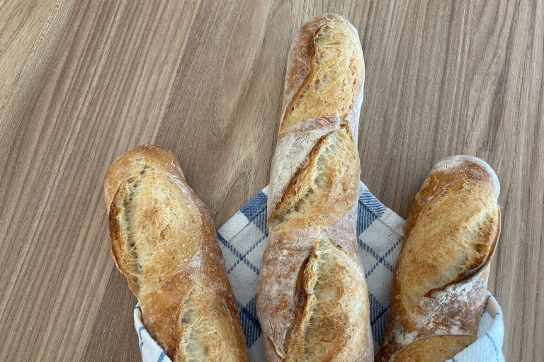 Baguettebacken leicht gemacht Drei frisch gebackene Baguettes auf einem blauen Geschirrtuch.